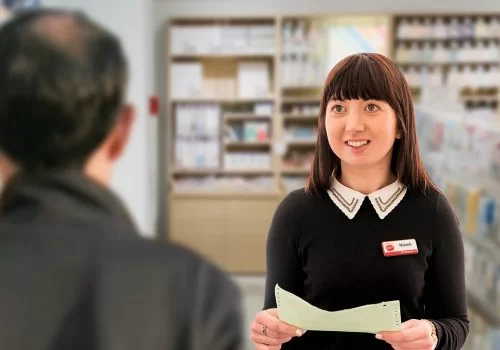 A McGreals pharmacist speaking privately with a customer at the counter